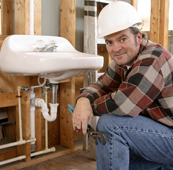 A plumber sitting next to a faucet