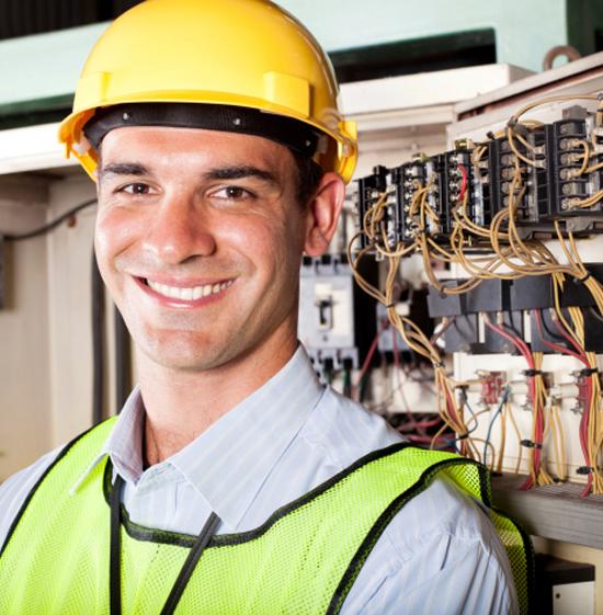 An image of a smiling electrician with electric switches in the background